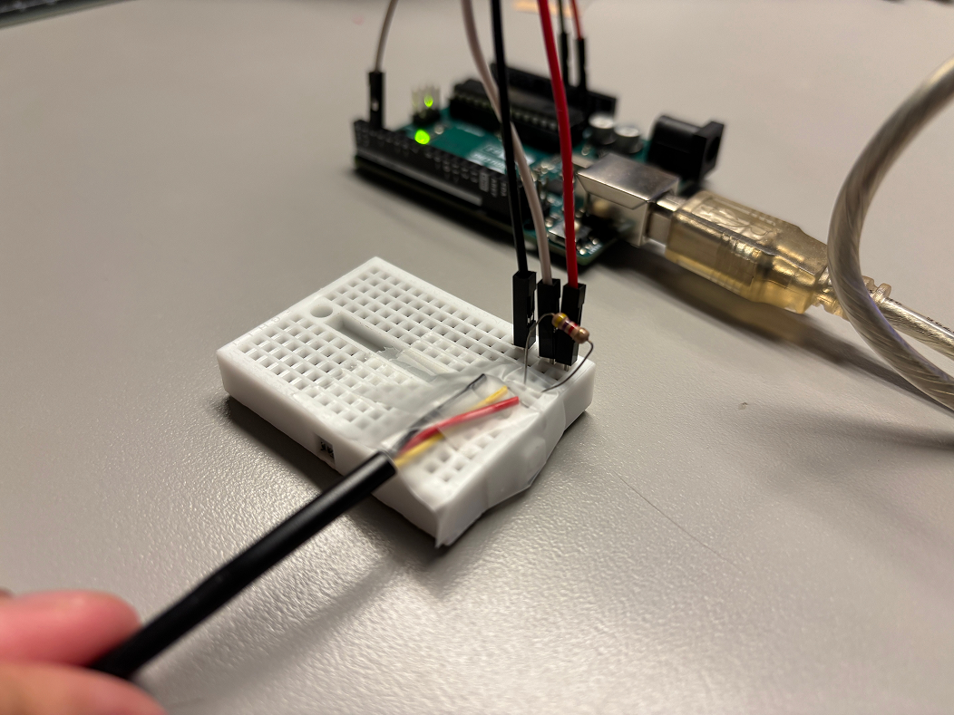 Taping the wires onto the breadboard. Unlike regular copper wires, these ones were not thick enough and would therefore get detached from the breadboard frequently. Our goal was to find a better solution later in the process.